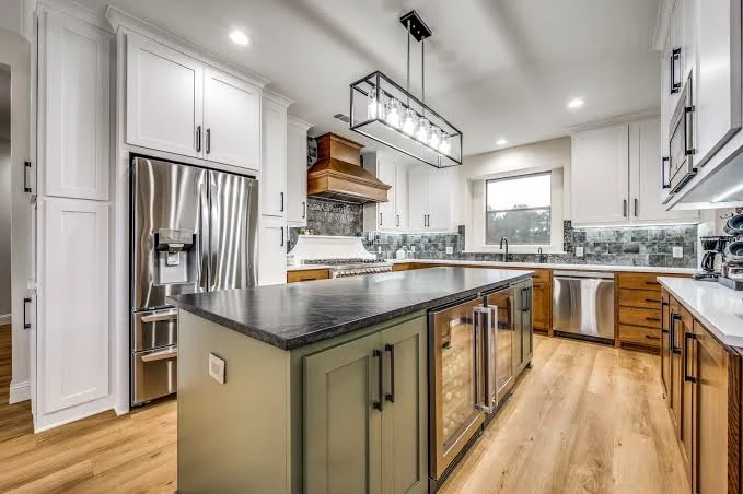 Kitchen island with a dark countertop, green cabinetry, and integrated beverage storage