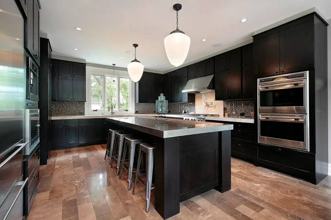 Kitchen with dark cabinetry, a central island, metal stools, and white pendant lights
